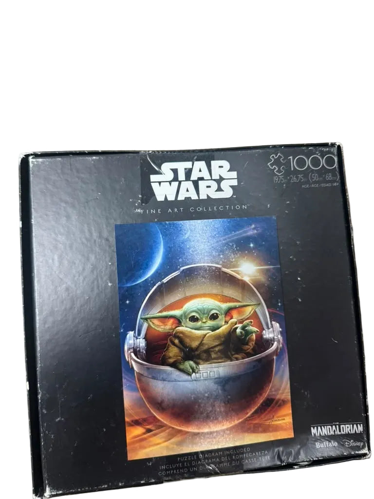 Star Wars The Art Collection 1000-piece jigsaw puzzle box featuring Grogu on a spaceship, photographed on a wooden tabletop.
